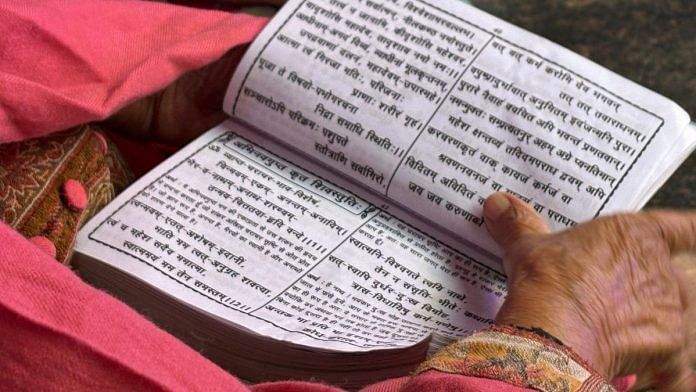 A woman at Kheer Bhawani temple in Ganderbal reading prayers from Kashmiri Pandits praying book. | Anisha Nehra | ThePrint