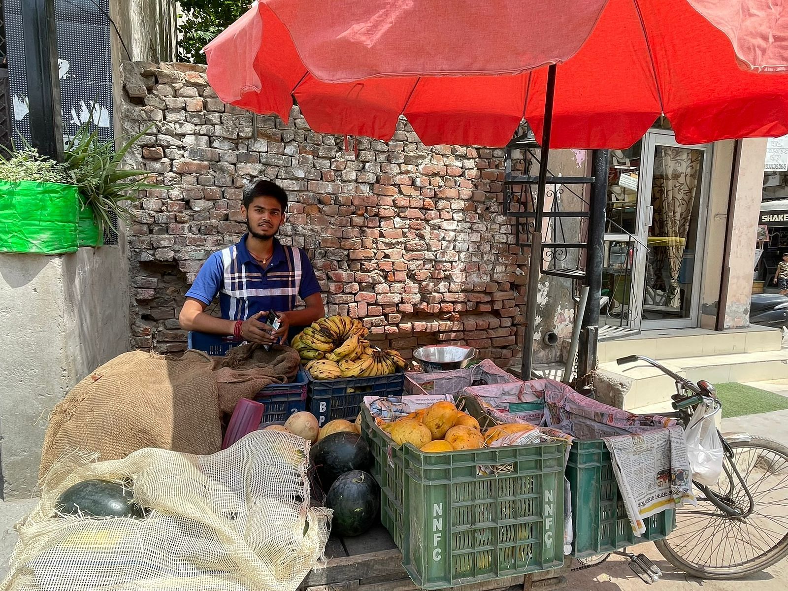 Young street vendor Vishal Jaiswal stands by his fruit cart in Arjun Nagar, Old Gurugram, near the original Om Sweets outlet.