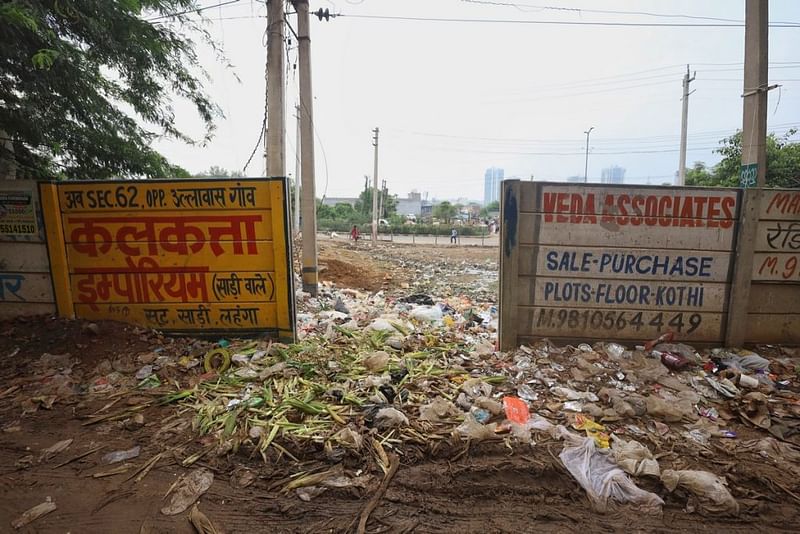 टूटी हुई बाउंड्री वॉल के उस पार एक खाली ज़मीन, जो अब डंपिंग ग्राउंड बन चुकी है | फोटो: मनीषा मोंडल/दिप्रिंट