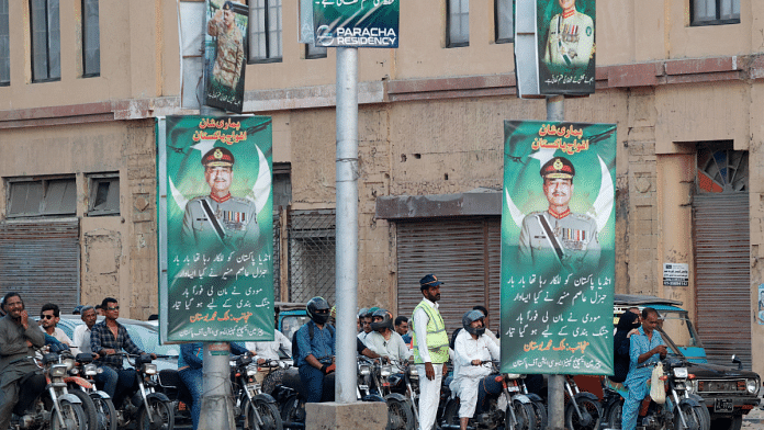 A police officer stands in front of the traffic, next to posters of the Chief of Army Staff of Pakistan Asim Munir, in Karachi, on 20 May 2025. | File Photo | Akhtar Soomro | Reuters