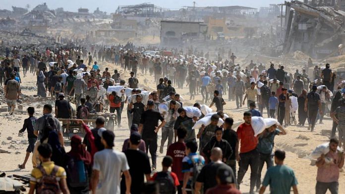 Palestinians carry aid supplies amid a hunger crisis in the northern Gaza Strip Sunday | Photo: Reuters