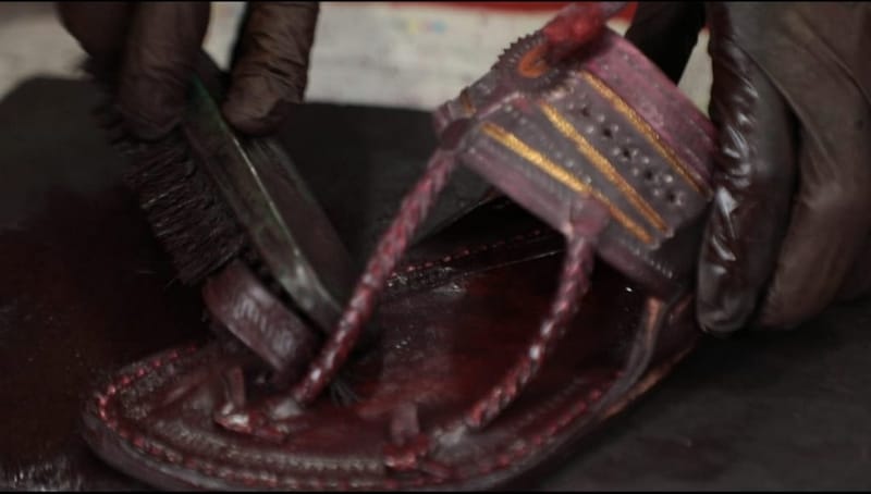 एक स्थानीय कारीगर चमड़े की कोल्हापुरी चप्पल को हाथ से पॉलिश करता है, जिससे उसका रंग हल्के भूरे से गहरे भूरे में बदल जाता है. हर जोड़ी को हाथ से फिनिश किया जाता है | फोटो: मोहम्मद हम्माद/दिप्रिंट