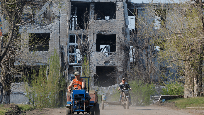 Men ride vehicles near a building destroyed in the course of Russia-Ukraine conflict in Toshkivka (Toshkovka) in the Luhansk region, a Russian-controlled area of Ukraine, April 17, 2025 | Reuters