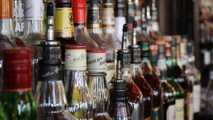 A photo of various bottles of alcohol lined up on a bar.