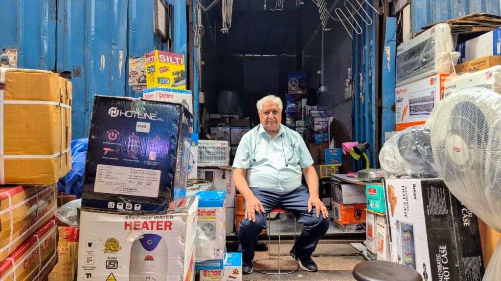 Kumar at his shop made of cardboard boxes. He had lost his shop to fire in Bhagirath Palace in 2022 | Shubhangi Misra | ThePrint