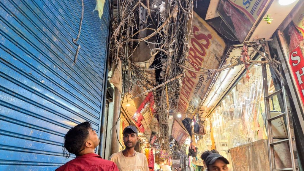 A man looks at the glut of wires above him in Delhi's Vardhaman Market | Shubhangi Misra | ThePrint