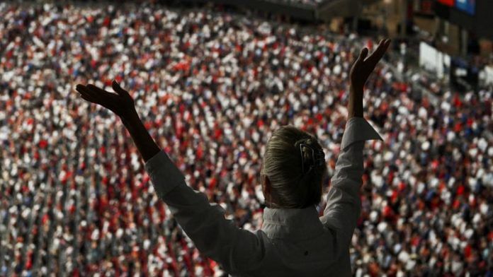A person raises their arms while attending a memorial service for slain conservative commentator Charlie Kirk at State Farm Stadium, in Glendale, Arizona, on 21 September 2025. | Callaghan O'Hare | Reuters