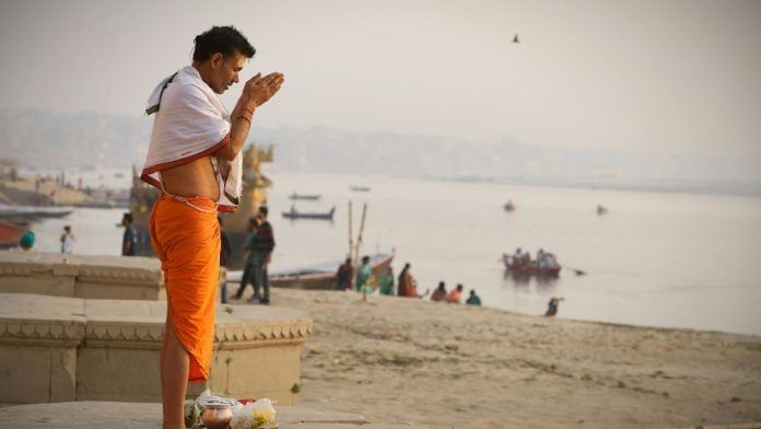 A Hindu man offers prayers by a river