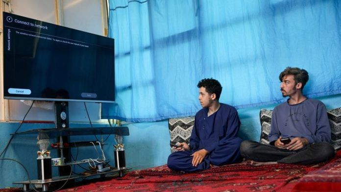 Men try to connect their smart TV to the internet inside their home, amid telecom shutdown across the country, in Kabul on 30 September 2025. | Sayed Hassib | Reuters