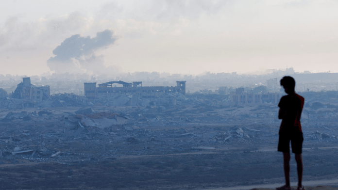 A displaced Palestinian boy looks on as smoke rises during an Israeli military operation in Gaza City, as seen from the central Gaza Strip, October 1, 2025 | Reuters