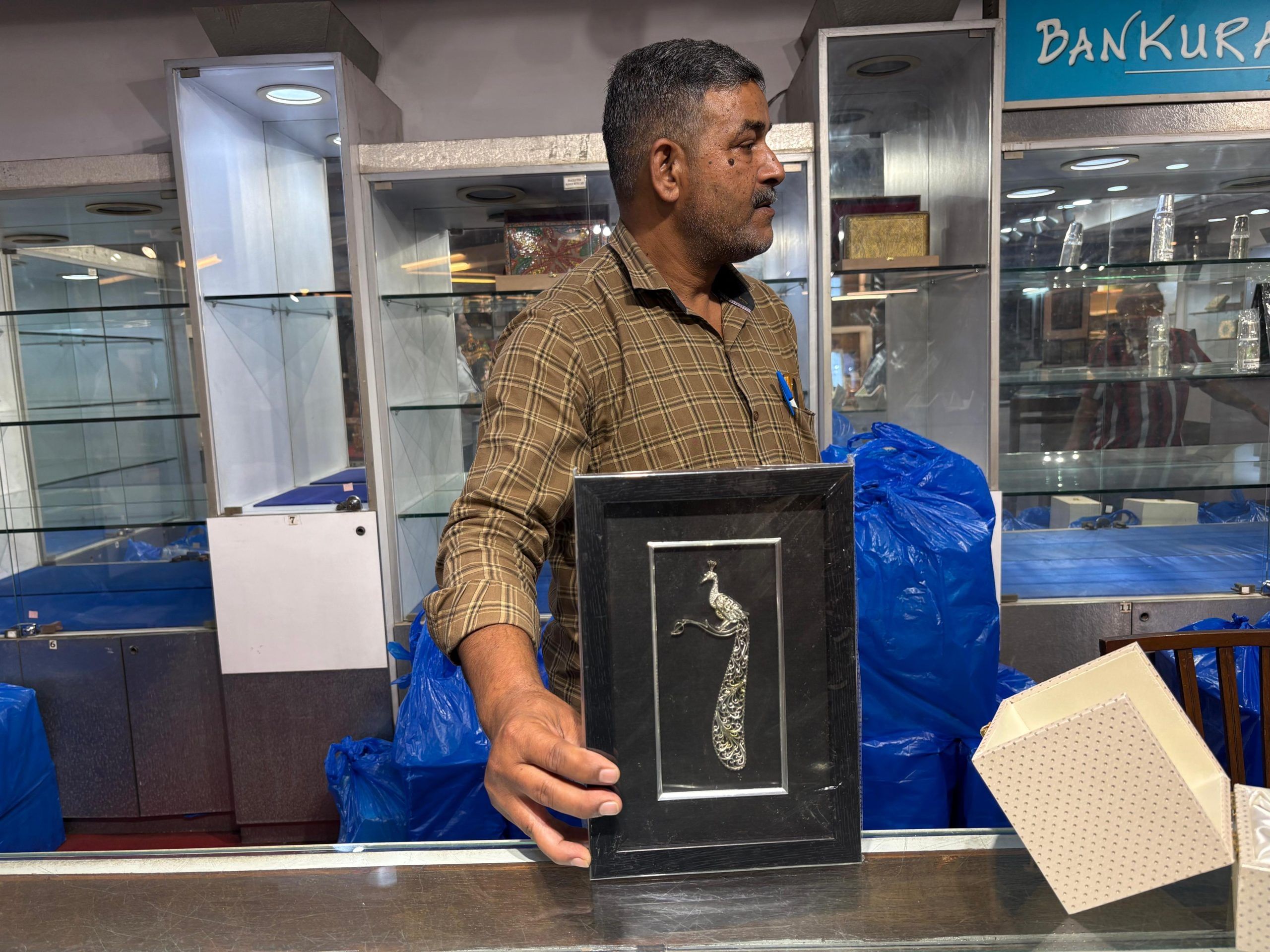 Ajay Singh, support manager at the emporium, unpacks boxes of newly arrived silverware—behind him, the shelves remain empty | Photo: Sakshi Mehra