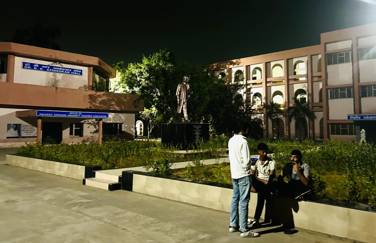 Men sitting outside the teachers unit after 7 pm