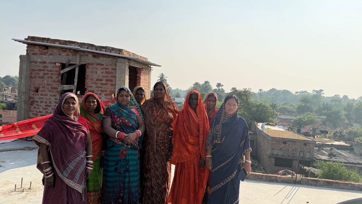 Anita Devi, Dilip’s wife in a blue saree, and neighbourhood women sit on the rooftop of Dilip’s house, watching his latest videos. Photo: Jyoti Yadav, ThePrint