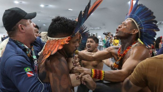 An Indigenous demonstrator is held by a staff member as protesters force their way into the venue hosting the UN Climate Change Conference (COP30), in Belem on 11 November 2025. | Anderson Coelho | Reuters