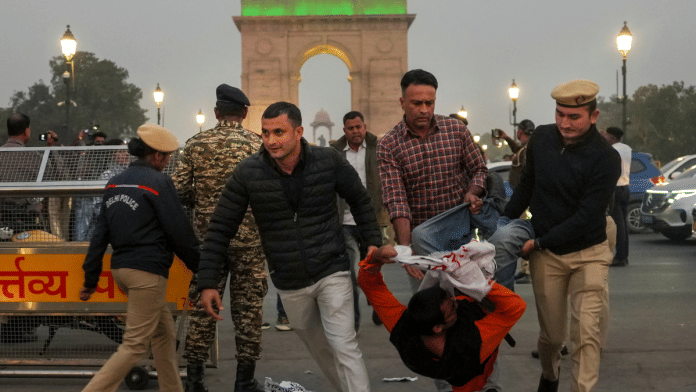 Police detain a protester during the air pollution protest near India Gate on Sunday | PTI
