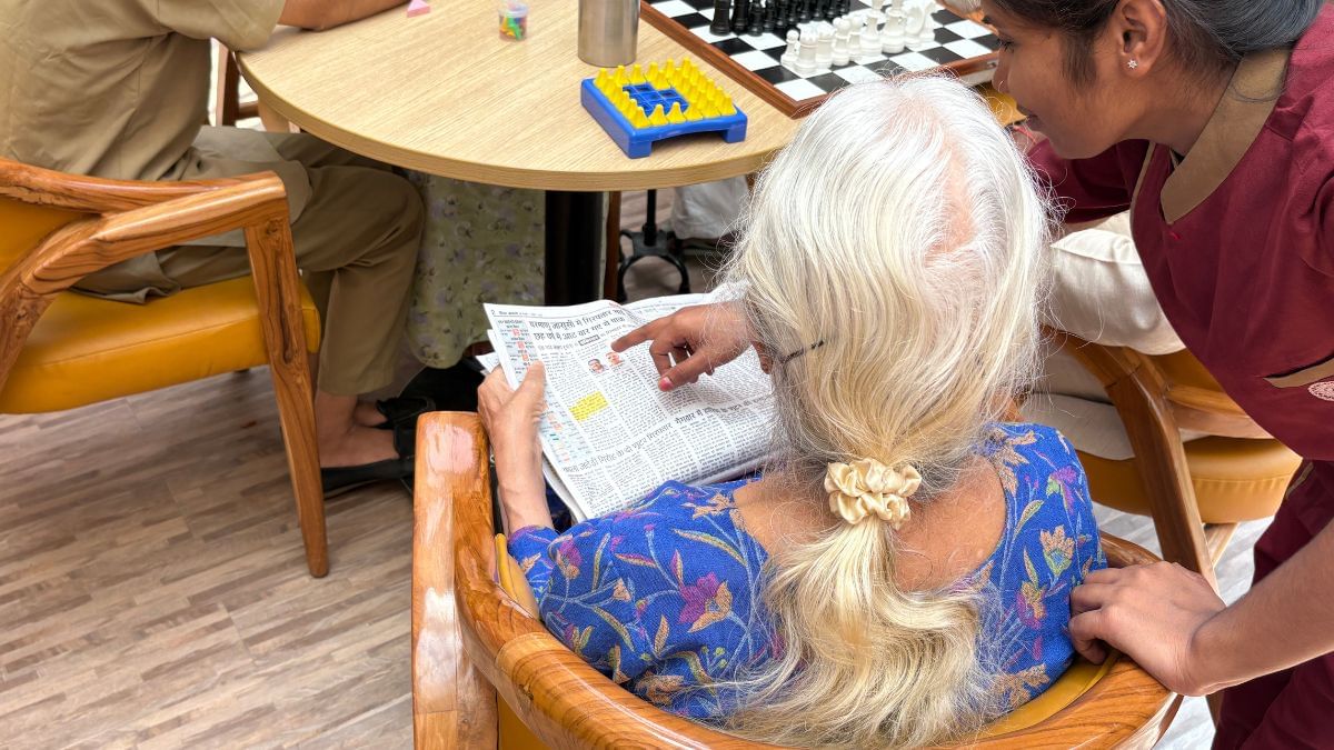 A staff member at Antara helps a resident read the newspaper | Sakshi Mehra, ThePrint 