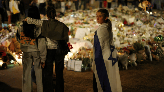 A girl wearing an Israeli flag stands next to floral tributes honouring the victims of a shooting at Jewish holiday celebration on Sunday at Bondi Beach, in Sydney, Australia, December 16, 2025 | Reuters